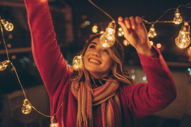 New Year's party preparations Photo of a young woman who is hosting New Year's party and having the last preparations on the venue - charming balcony over the city new year urban scene horizontal people stock pictures, royalty-free photos & images