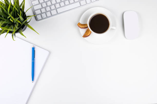 istock Office desk with copy space. Digital devices wireless keyboard and mouse on office table with notepad and cup of coffee, top view 686639398