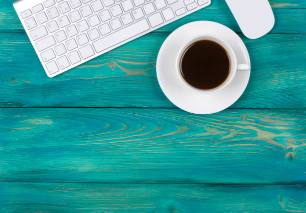 istock Office desk with copy space. Digital devices wireless keyboard and mouse on red wooden table with cup of coffee, top view 686639450