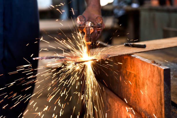 istock Worker cutting metalsheet by acetylene torch with bright sparks in fabication factory. 686645632