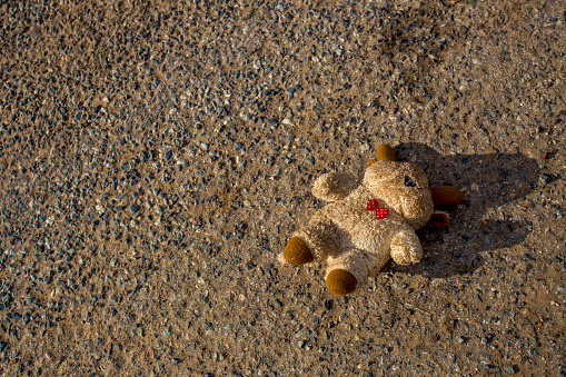 A lost bear doll fall down and lost on the street. The bear is dirty and lost it eye.