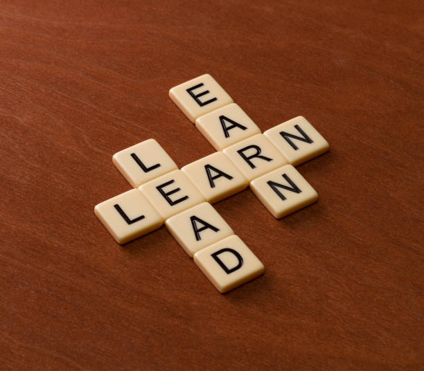 Crossword puzzle with words Learn, Lead and Earn. Leadership concept. Ivory tiles with capital letters on mahogany board.