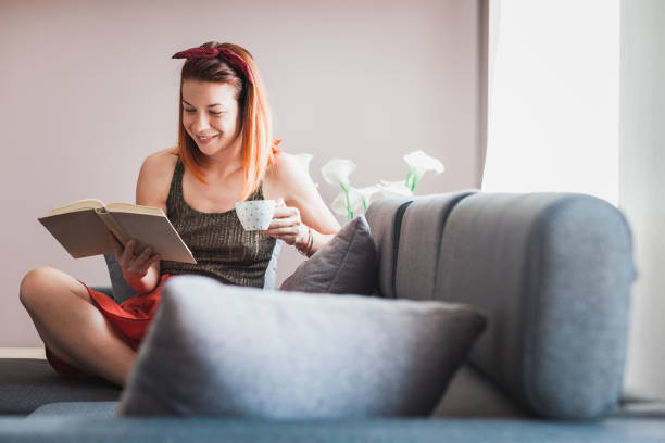 istock Young woman drinking coffee reading book 686684774
