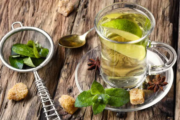 Tea brewed with lime and mint on wooden background