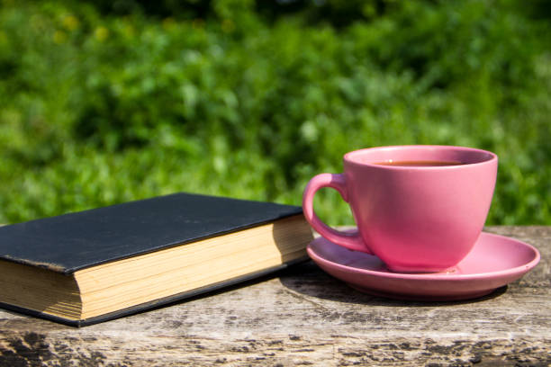 istock Coffee cup and old book on rustic wooden table outdoor 686709580