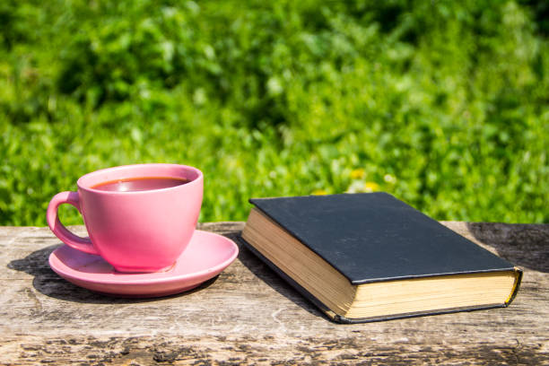 istock Coffee cup and old book on rustic wooden table outdoor 686709582