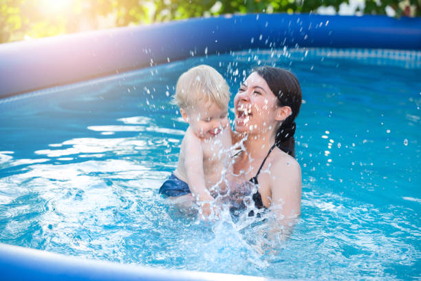 Happy young mother and her little son, having fun in outdoor swimming pool stock photo