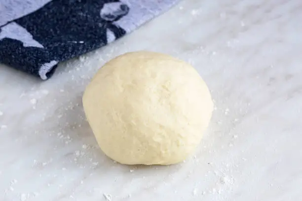 Homemade dough for german flammkuchen or french tarte flambé. On white table. Natural light, selective focus.