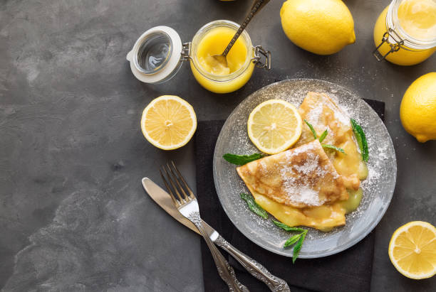 Fresh homemade crepes with lemon curd on gray concrete background.