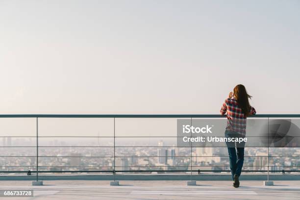 Woman Using Mobile Phone At Rooftop During Sunset With Copy Space Communication Or Lonely People Concept Stock Photo - Download Image Now