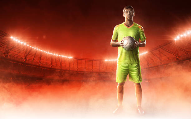 istock soccer player on a stadium with a ball on red background 686737622