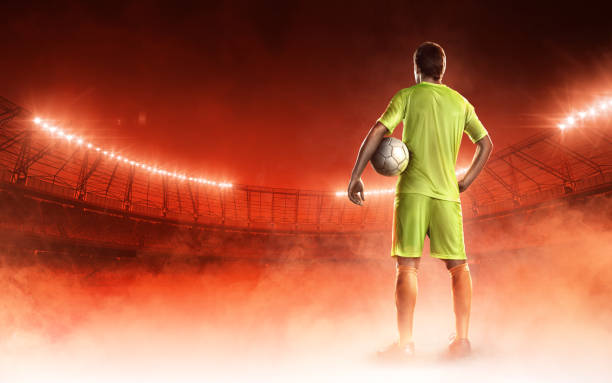 istock soccer player on a stadium with a ball on red background 686737692