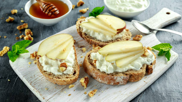 istock Appetizer bruschetta with pear, honey, walnut and cottage cheese on white board. 686747554