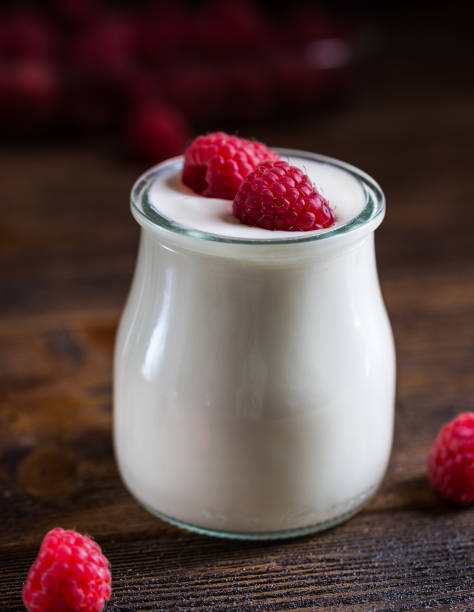 istock White yogurt with raspberries in glass bowl on rustic table. 686765416