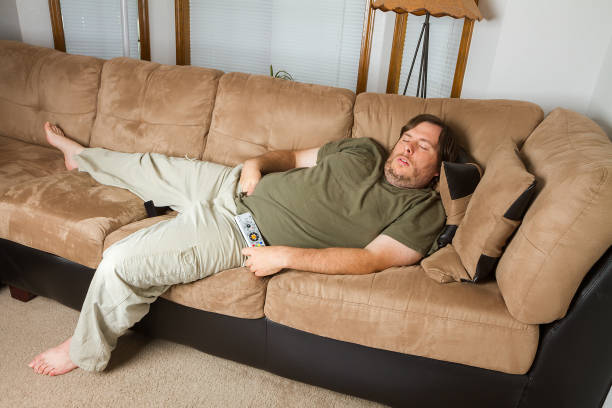 man asleep on the couch - remote fat overweight dieting imagens e fotografias de stock