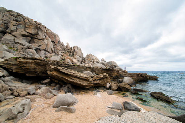 istock A man is standing on a huge stone on the dramatic beach in Sardinia, Italy. 686780060