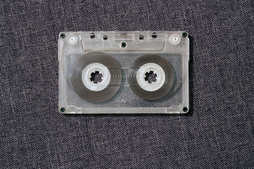 Old worn scratched audio cassette on a gray background