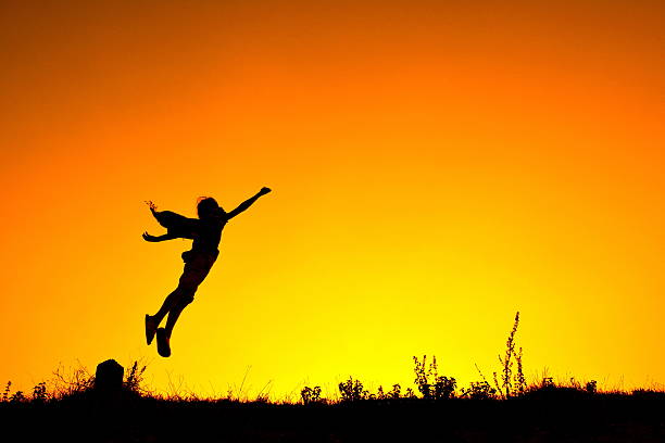 istock Silhouette Person Jumping In Mid-Air Against Orange Sky 686786043