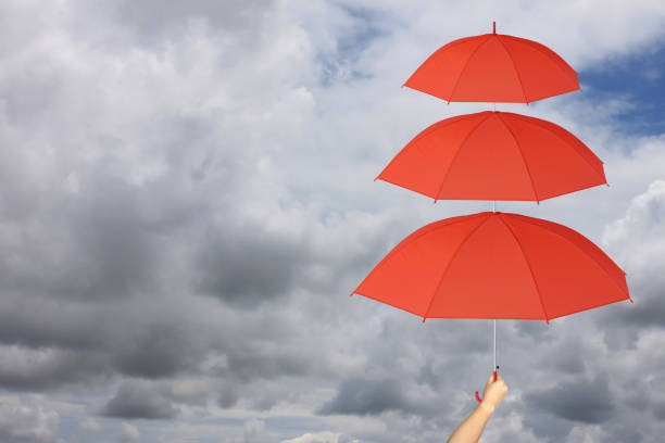 Red umbrella third layers in hand and rain protection more than,concept for management business idea on rain cloud background.