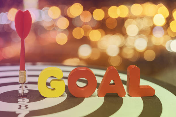 istock Dart target arrow on bullseye with goal words over bokeh background 686823434