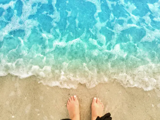 Photo of Feet on Sandy Beach with Water