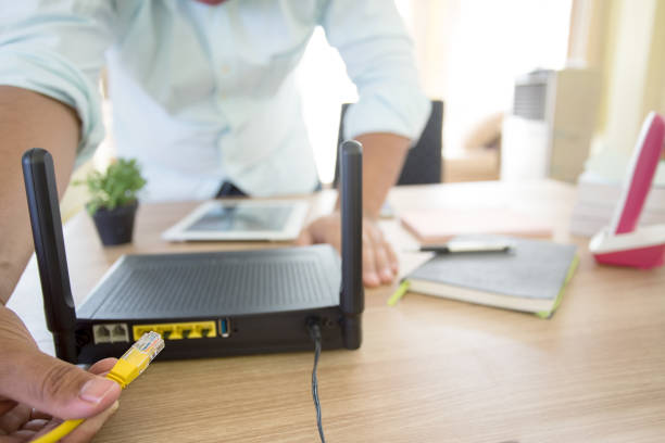 hand and lan network cable with people work on wireless router, stock photo