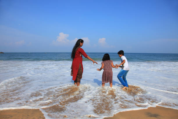 Kids having fun with their mother in Kovalam beach in Kerala.
