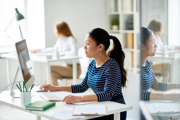 Asian Programmer Working on Project Profile view of pretty Asian programmer working on ambitious project while sitting in modern open plan office, waist-up portrait photo editor photos stock pictures, royalty-free photos & images