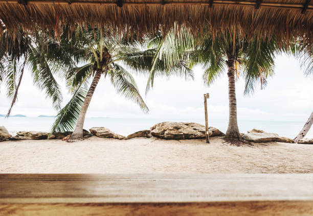 Tropical beach in summer, wood table top with blurred coconut trees, sand and the beach background