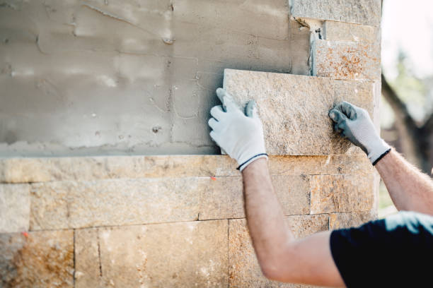 operaio edile che installa pietra sulla facciata architettonica di un nuovo edificio. dettagli dell'industria edile - grouting foto e immagini stock