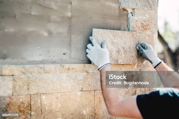 Construction Worker Installing Stone On Architectural Facade Of New Building Details Of Construction Industry Stock Photo - Download Image Now