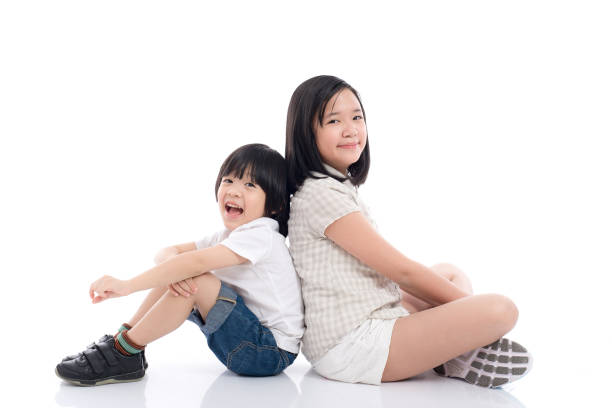 Two  happy asian children sitting and leaning on each other ,white background isolated