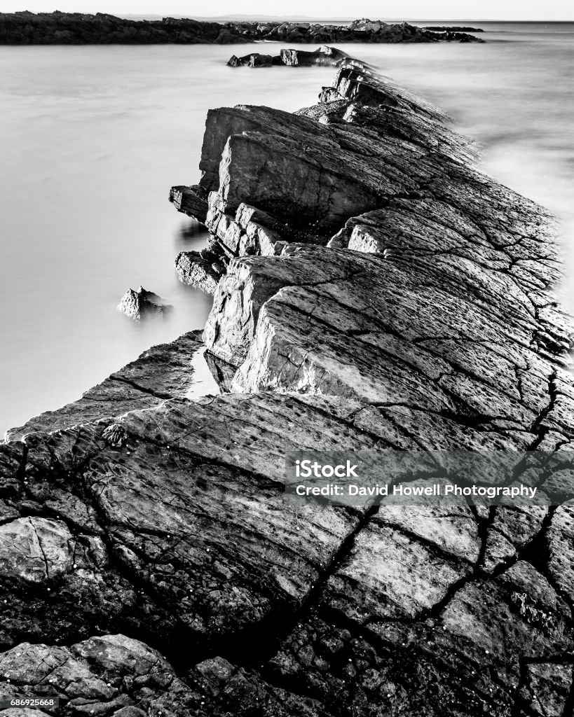 Rising from the sea A black and white long exposure of the rocks on the Craighead coast in Scotland. Black And White Stock Photo