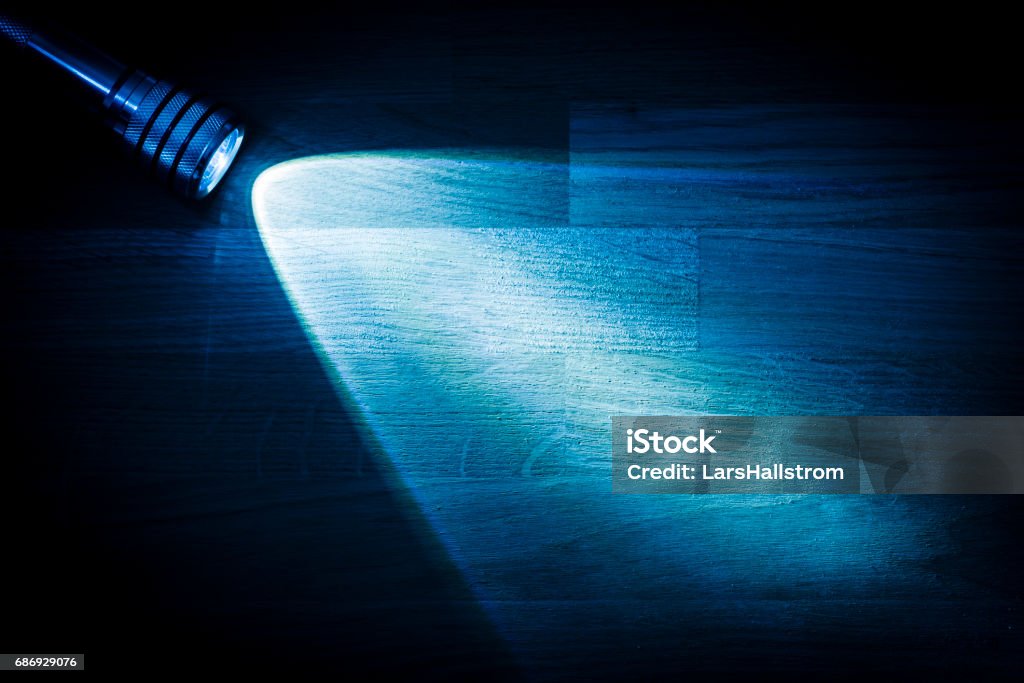 Flashlight shining a beam of light in darkness Flashlight and a beam of light in darkness. A modern led light with bright projection on dark wood table. Surface with copy space. Flashlight Stock Photo