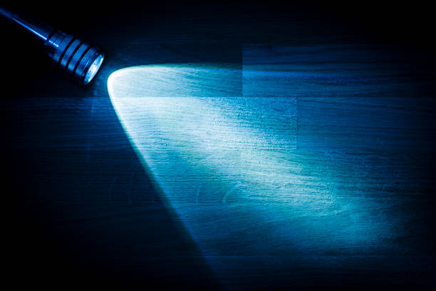 Flashlight shining a beam of light in darkness Flashlight and a beam of light in darkness. A modern led light with bright projection on dark wood table. Surface with copy space. searchlight photos stock pictures, royalty-free photos & images
