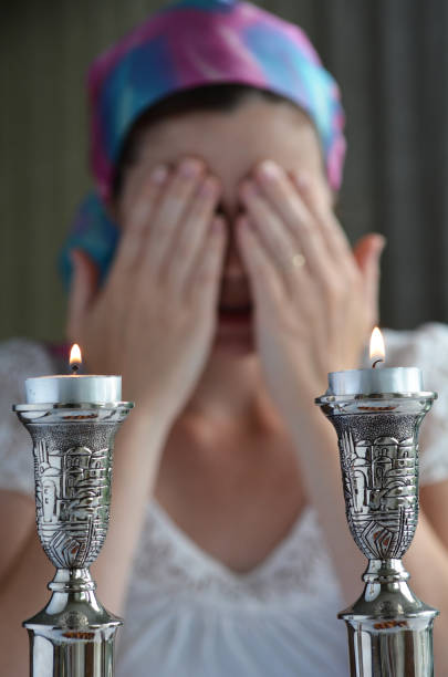 Shabbat eve Jewish woman says the blessing upon lighting the sabbath candles before shabbat eve dinner. jewish sabbath photos stock pictures, royalty-free photos & images
