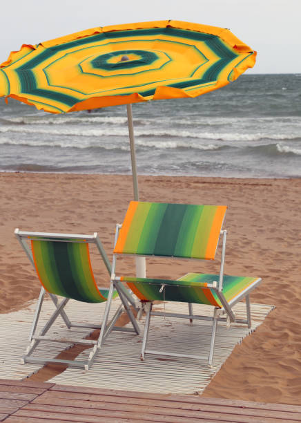 umbrellas and sunbeds on the beach during a windy day - nodoby imagens e fotografias de stock
