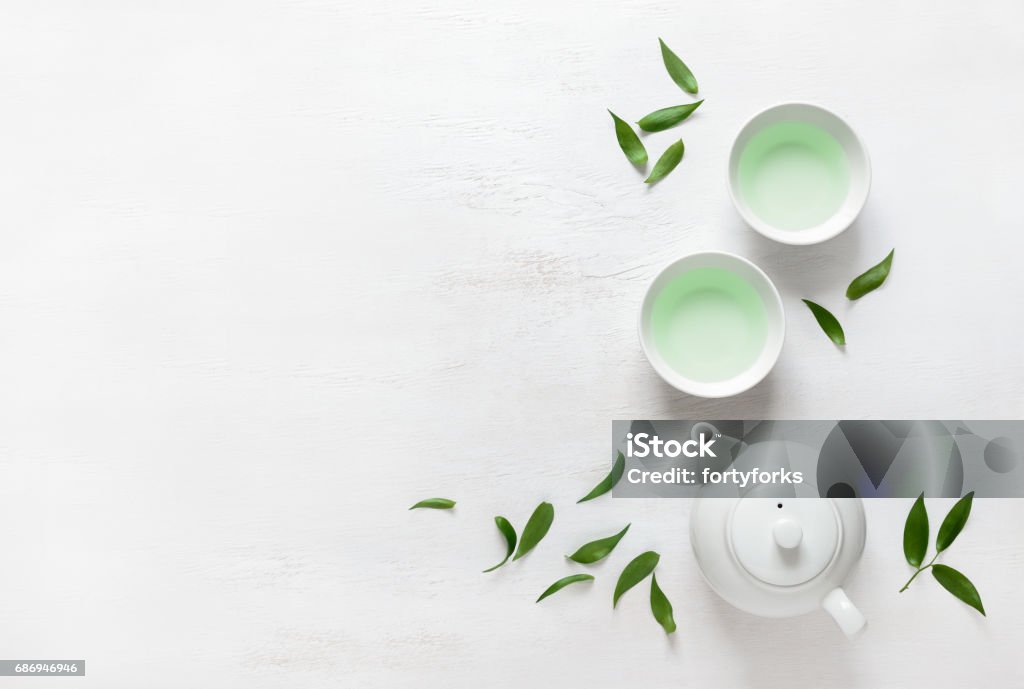 Tea concept, view from above Tea freshly brewed in a teapot and two cups, surrounded with fresh tea leaves, top view composition, space for a text Cup Stock Photo