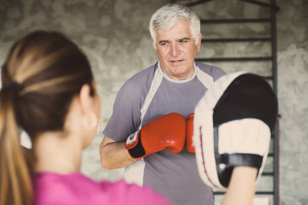 istock Older man boxing in gym. Senior man with personal trainer. 686956434