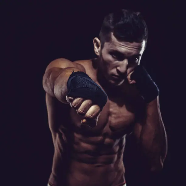 MMA Fighter Preparing Bandages For Training. Dark background.