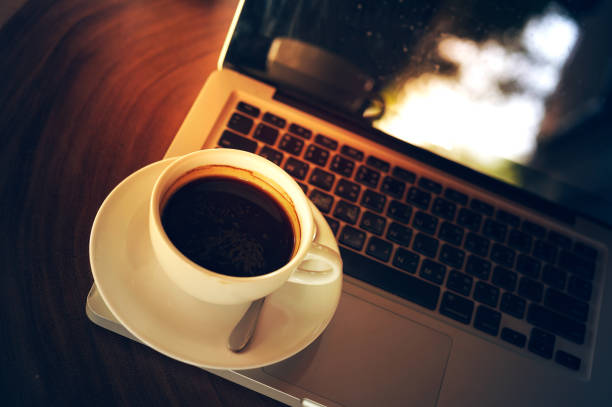 istock Cup of coffee and laptop on wooden table 686964230