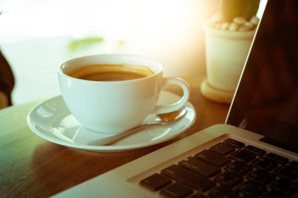 istock Cup of coffee and laptop on wooden table 686964522