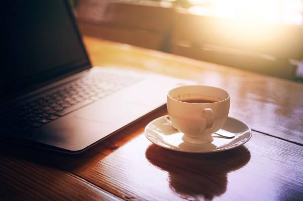 istock hot coffee cup and laptop on wood table 686964630
