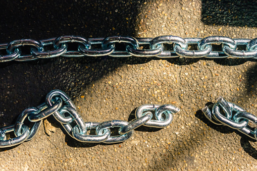 Chain and breaking chain on concrete floor background with light and shadow, vintage concepts.