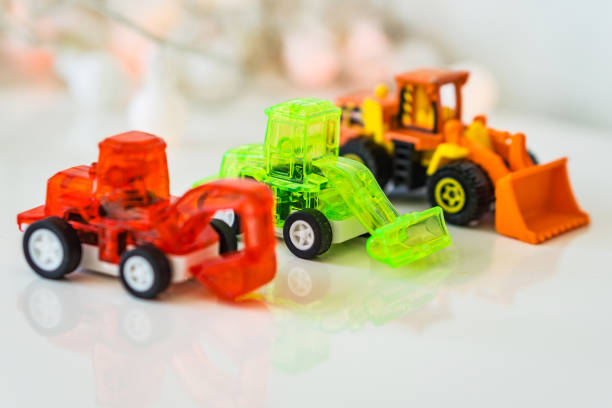 istock Toys green loader, red blurred excavator and orange blurred loader, background bokeh. Concept motor skills. 686967894