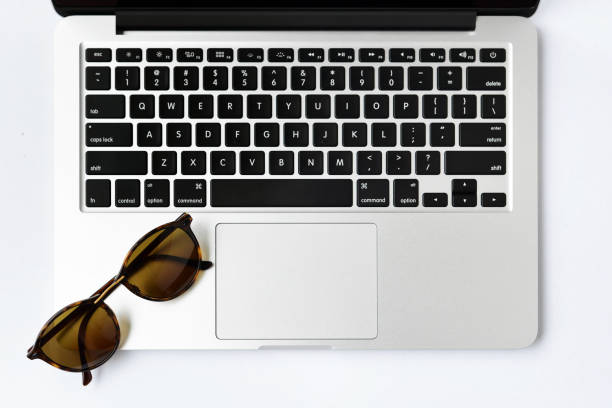 istock Sunglasses and computer keyboard on white background - taken in natural light with strong shodow to create realistic indoor mood 686972586