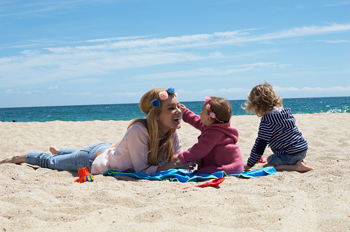 Happy family on beach vacation. They are sitting on the sand and enjoying playing.