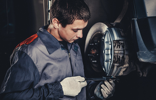Professional car mechanic repairing brakes in auto repairing shop
