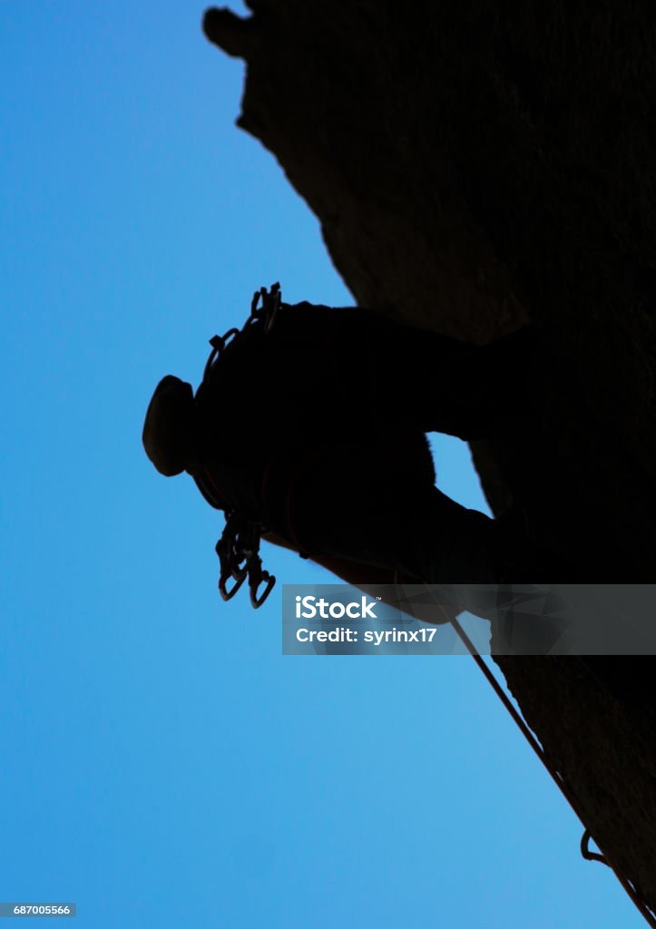 Rock climber with climbing equipment. Bottom up photography of a male rock climber with climbing equipment. Photo taken in National park Paklenica, Croatia, in summer, with beautiful blue sky. Achievement Stock Photo