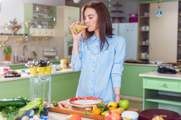 istock Slim young woman standing in kitchen drinking fresh juice 687010738